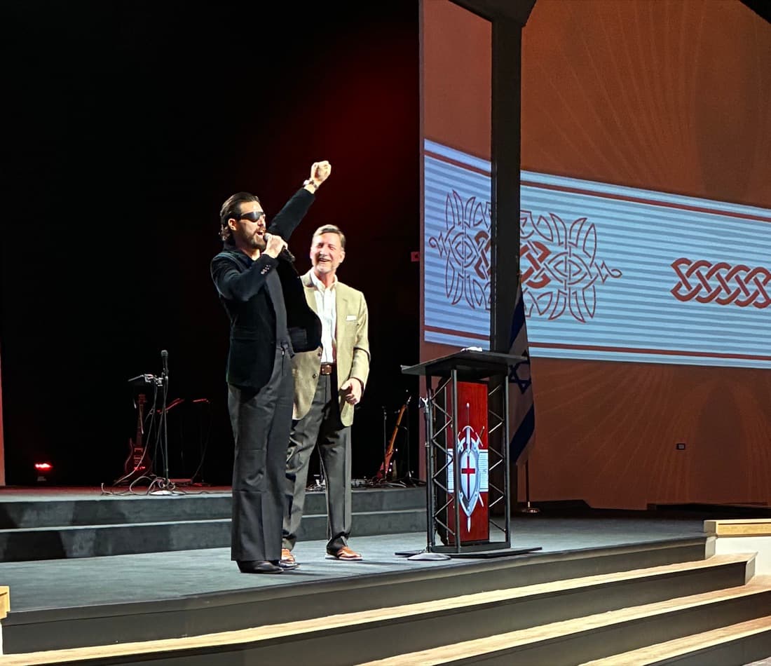 Enrico Omri Ravenna on stage, arm raised