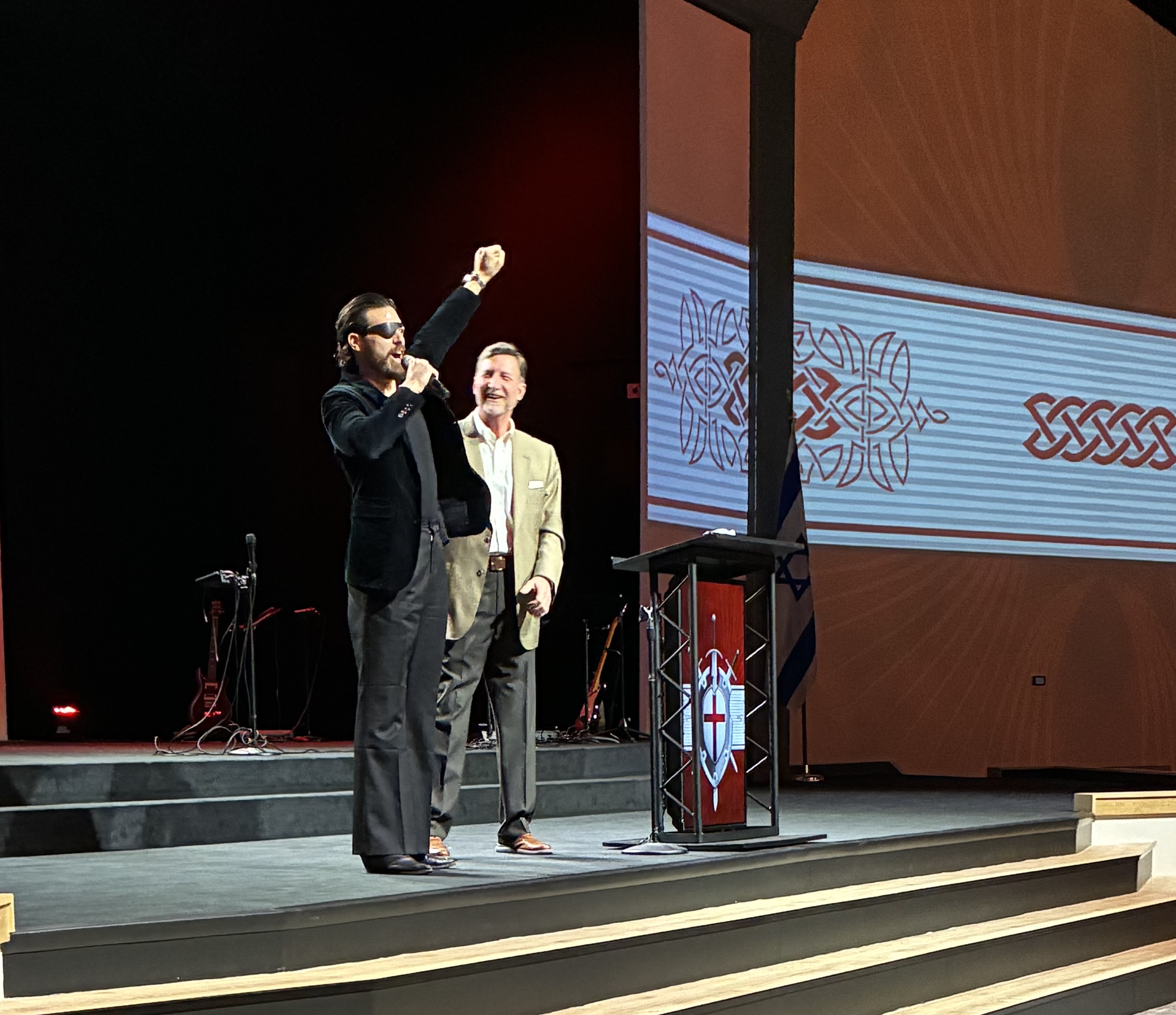 Enrico Omri Ravenna on stage, arm raised